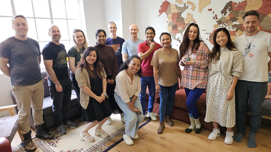 Smiling TMF staff and Timor team gathered in front of a map background